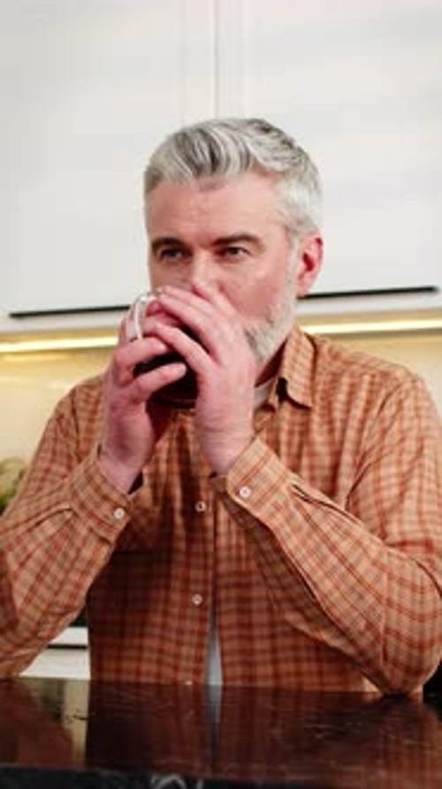 Gray-Haired Man Enjoys Coffee in Modern Kitchen