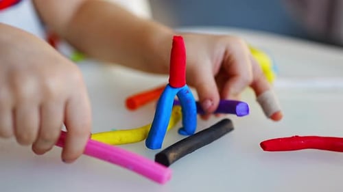Little Girl Plays with Multicolored Plasticine Creates Different Shapes