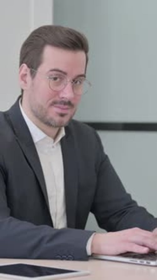 Man in Suit Gives Thumbs Up at Desk