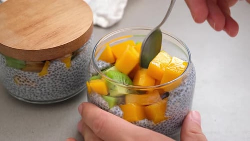 Chia-Pudding mit Mango und Kiwi im Glas.