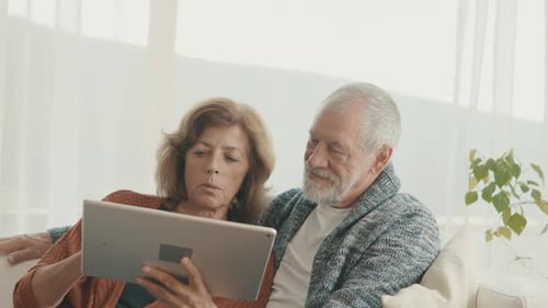 Senior Couple Relaxing on Sofa with a Tablet