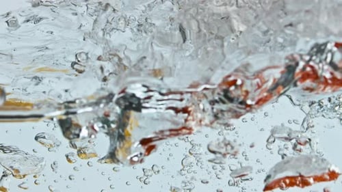 Red and Yellow Peppers Dropped in Water