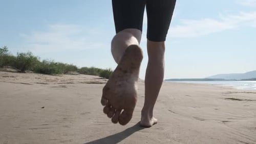 Man runs on a beach. Young sportive man runs barefoot on a sandy coast along the river