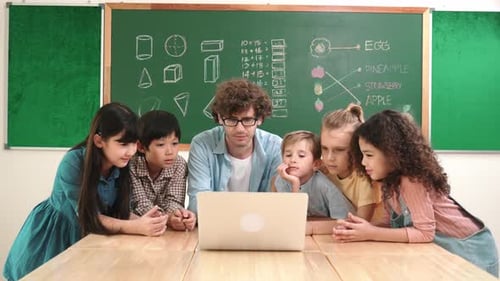 Enthusiastic Children Learning Together with Teacher Using Laptop