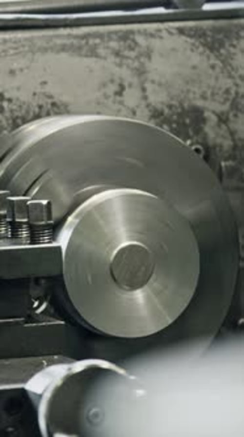 Metal shaping precision: worker operates lathe machine in workshop
