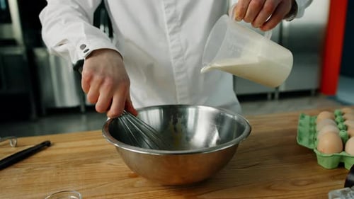 A chef adds milk to the pancake mix in a professional kitchen. making pancakes in a restaurant.
