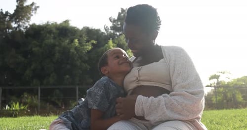 Une heureuse mère enceinte africaine passe un moment tendre avec son fils à Park Affection
