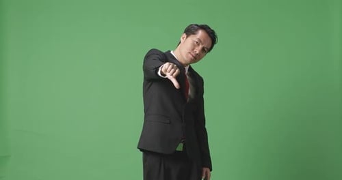 Asian Business Man Showing Thumbs Down Gesture While Standing In The Green Screen Studio