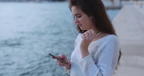 A Young Woman Joyfully Listening to Music While Enjoying the Serene Waterside Atmosphere