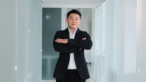 Smiling Man with Crossed Arms in Office Hallway