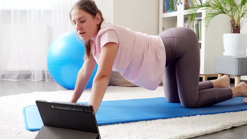 Young woman watching online video sports training and stretching on fitness mat