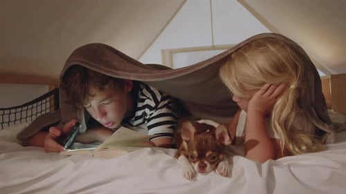 Siblings Enjoying Bedtime Story Under Cozy Blanket Fort