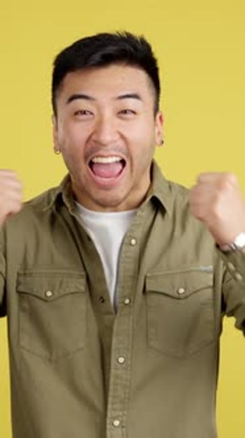 Excited Young Adult Celebrates Against Yellow Background