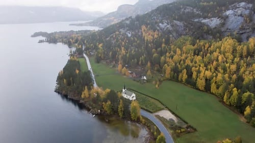 Petite église norvégienne dans une vallée aux couleurs automnales, nuages bas, brouillard et pluie. Depuis la région de Telemark