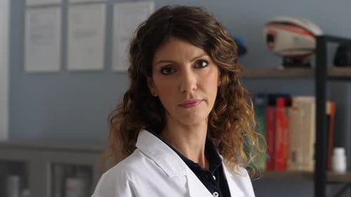 Beautiful and young female doctor staring at camera in office