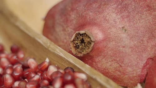 panning of pomegranate seeds to whole pomegranate in wooden plate juicing and using fresh ingredient