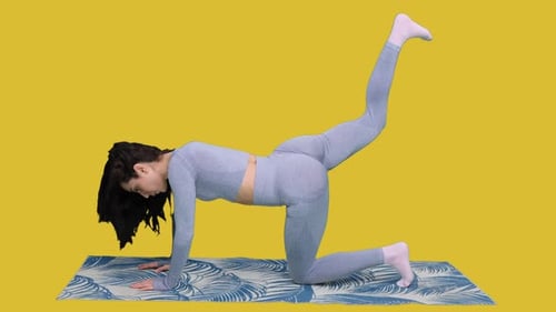 Fitness-Model trainiert Gesäß auf dem Boden auf einer Yogamatte auf dem gelben Chroma Key
