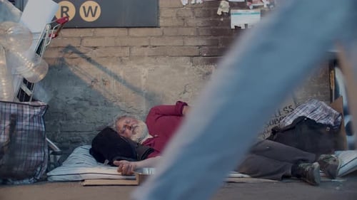 Senior Homeless Man Sleeping on Sidewalk as Pedestrians Donating Money to Him