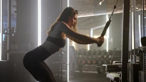 Eine fitte Frau nimmt an einer intensiven Trainingseinheit im Fitnessstudio teil und zieht konzentriert und entschlossen Gewichte