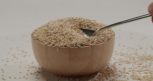 Wooden Bowl of Quinoa with Spoon on White