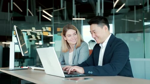 Colleagues Collaborate on Laptop in Modern Office