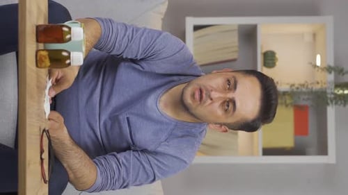 Vertical video of Man covering mouth and nose while sneezing.