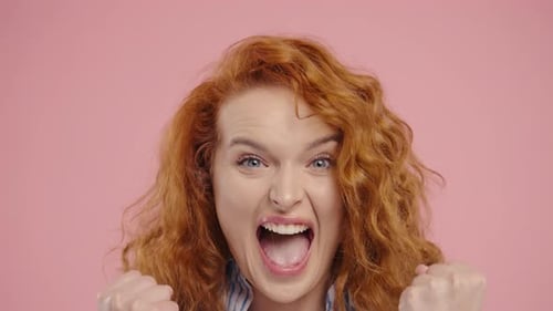Excited woman cheering with joy on pink background