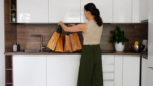 Mujer que lleva bolsas de supermercado reutilizables a la cocina después de la entrega a domicilio, prácticas compras de alimentos y