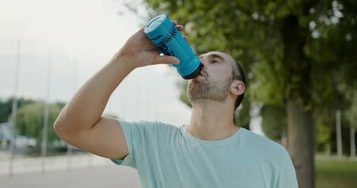 Man Drinks Water From Bottle Outdoors