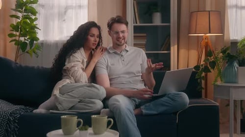 Couple Relaxing on Sofa Using Laptop Together