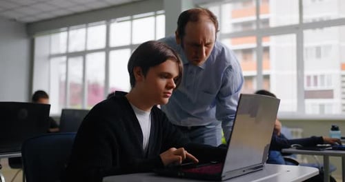 Educación en la escuela moderna: un profesor ayuda a un estudiante en el aprendizaje en el aula basado en computadora