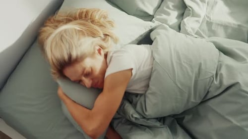 Woman Sleeping Peacefully in Bed with Green Linens
