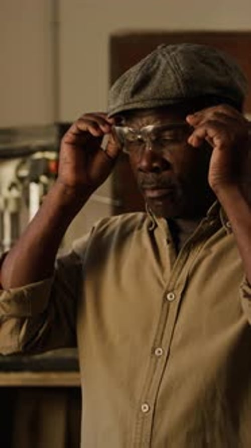 Man Puts on Safety Glasses in a Workshop