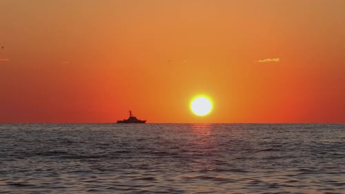 Silhouette of Ship on the Horizon with Vibrant Sunset