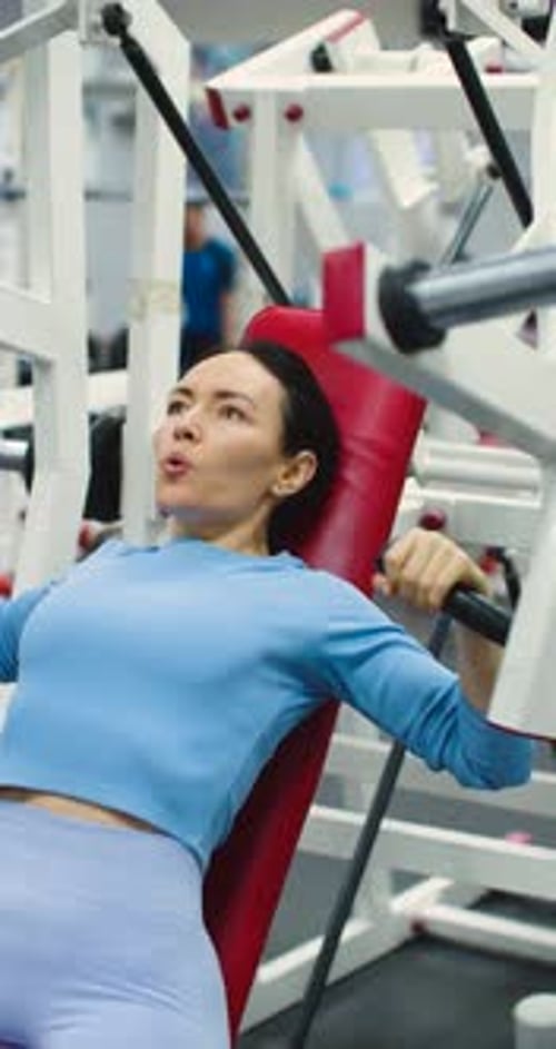 Woman Using Chest Press Machine at the Gym
