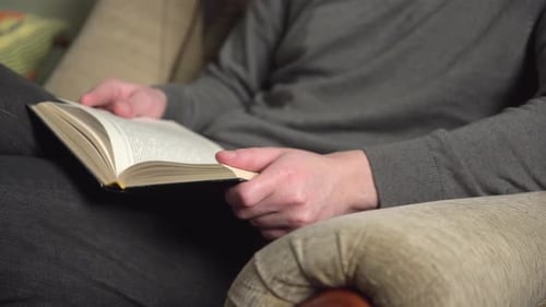 Person Relaxing and Reading Book on Couch