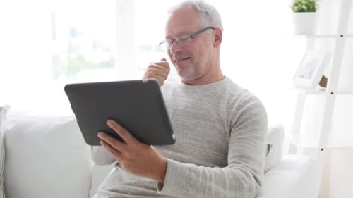 Senior Man Relaxing on Couch Using Tablet