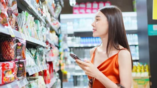 Asian young beautiful woman holding grocery basket walk in supermarket.