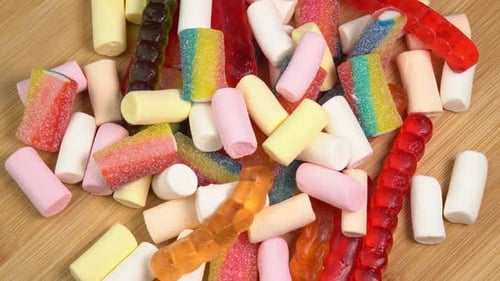 Mehrfarbige Gummibonbons, die sich auf einem Holzbrett drehen. Mehrfarbiges Gummibonbon-Gelee
