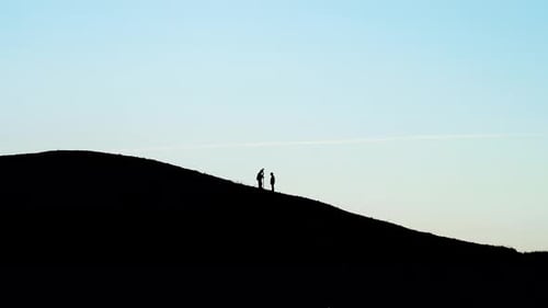 Silhouette von Männern, die topographische Vermessungen auf dem Gipfel eines schwarzen Hügels durchführen