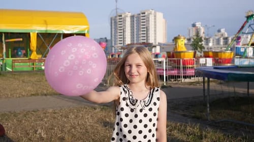 Happy Girl Holding Pink Balloon at Carnival