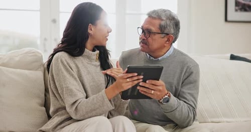 Woman Teaching Senior Man to Use Tablet at Home
