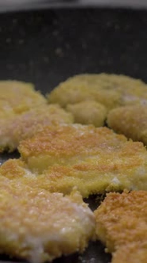 Cooking Breaded Chicken Pieces in Pan Using Spatula to Turn