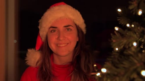 Smiling Woman With Santa Hat Next to Christmas Tree