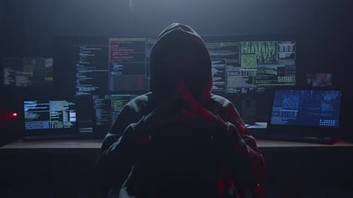 Un misterioso hacker se sienta en una habitación oscura rodeado de varios ordenadores