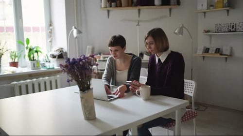 Two women working together on a laptop at home