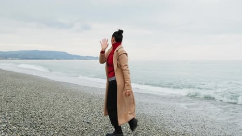Dansez pour une femme au manteau marron pour se débarrasser des angoisses près de l'océan