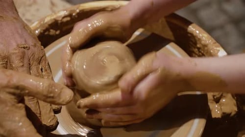 Unrecognizable Potter with Hands Covered with Clay Teaching Girl at Workshop How Making Beautiful