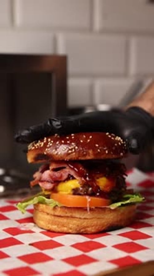 Gloved Hand Adds Top Bun to Delicious Hamburger