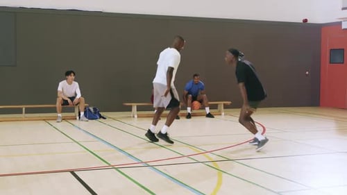 Diverse teammates starting one-on-one drill dribbling basketball, defending for practice at gym